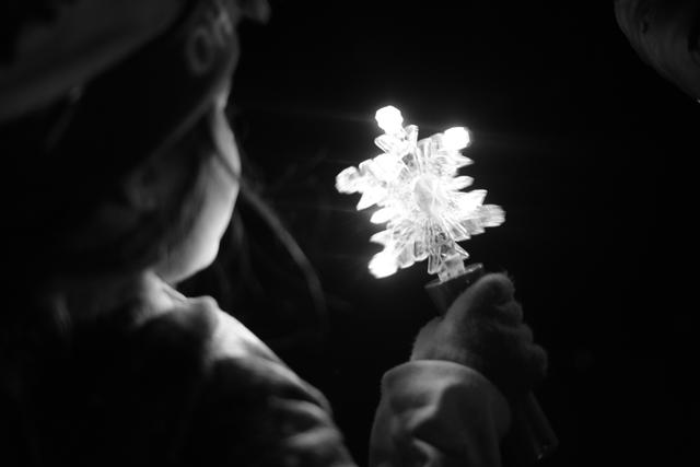 A child holding a glowing snowflake-shaped object in a dark setting