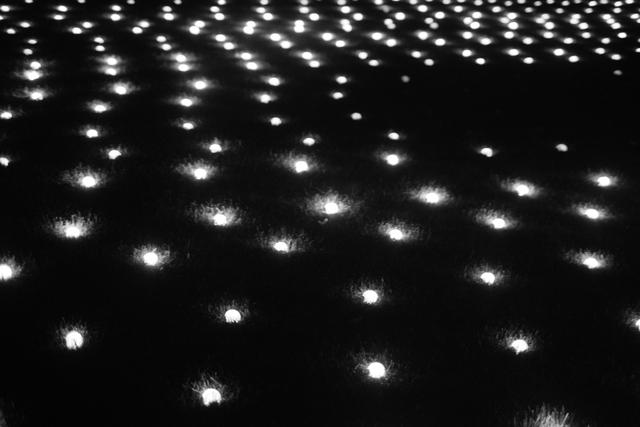 Numerous small lights arranged in a grid pattern on a dark surface, creating a glowing, starry effect
