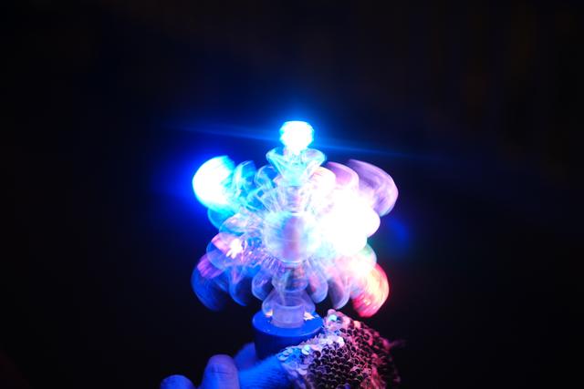 A glowing, multi-colored LED light toy with blue and pink lights against a dark background