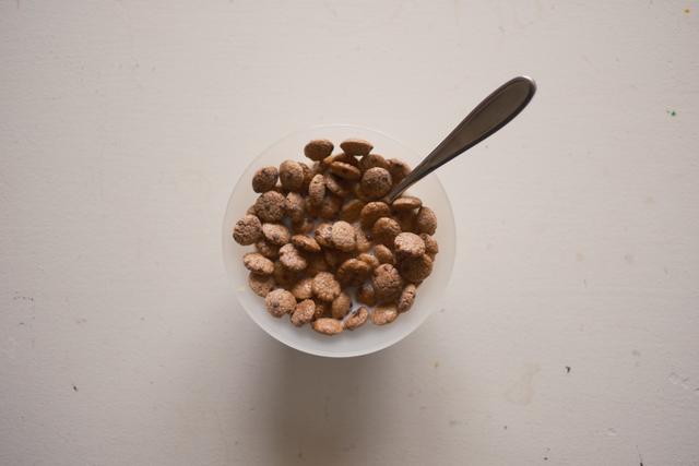 A bowl of cereal with a spoon on a white surface