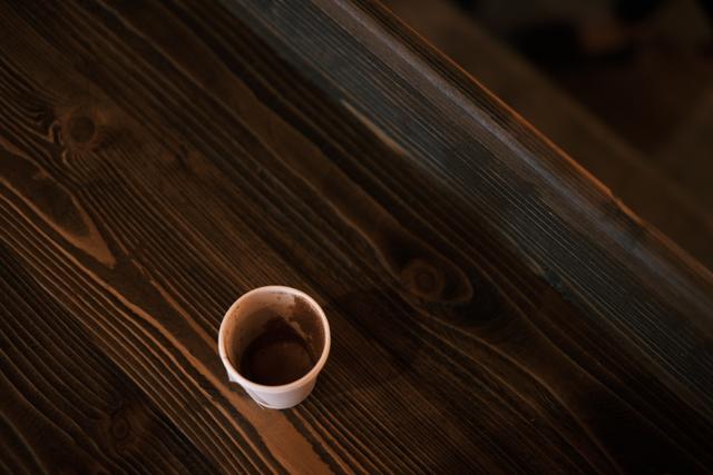 A nearly empty cup of coffee sits on a dark wooden table