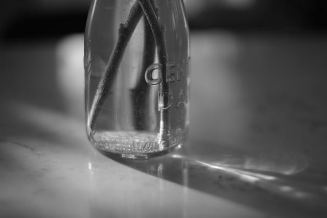 A close-up, black and white photo of a glass object casting a shadow on a surface, with a focus on its geometric shape and the play of light