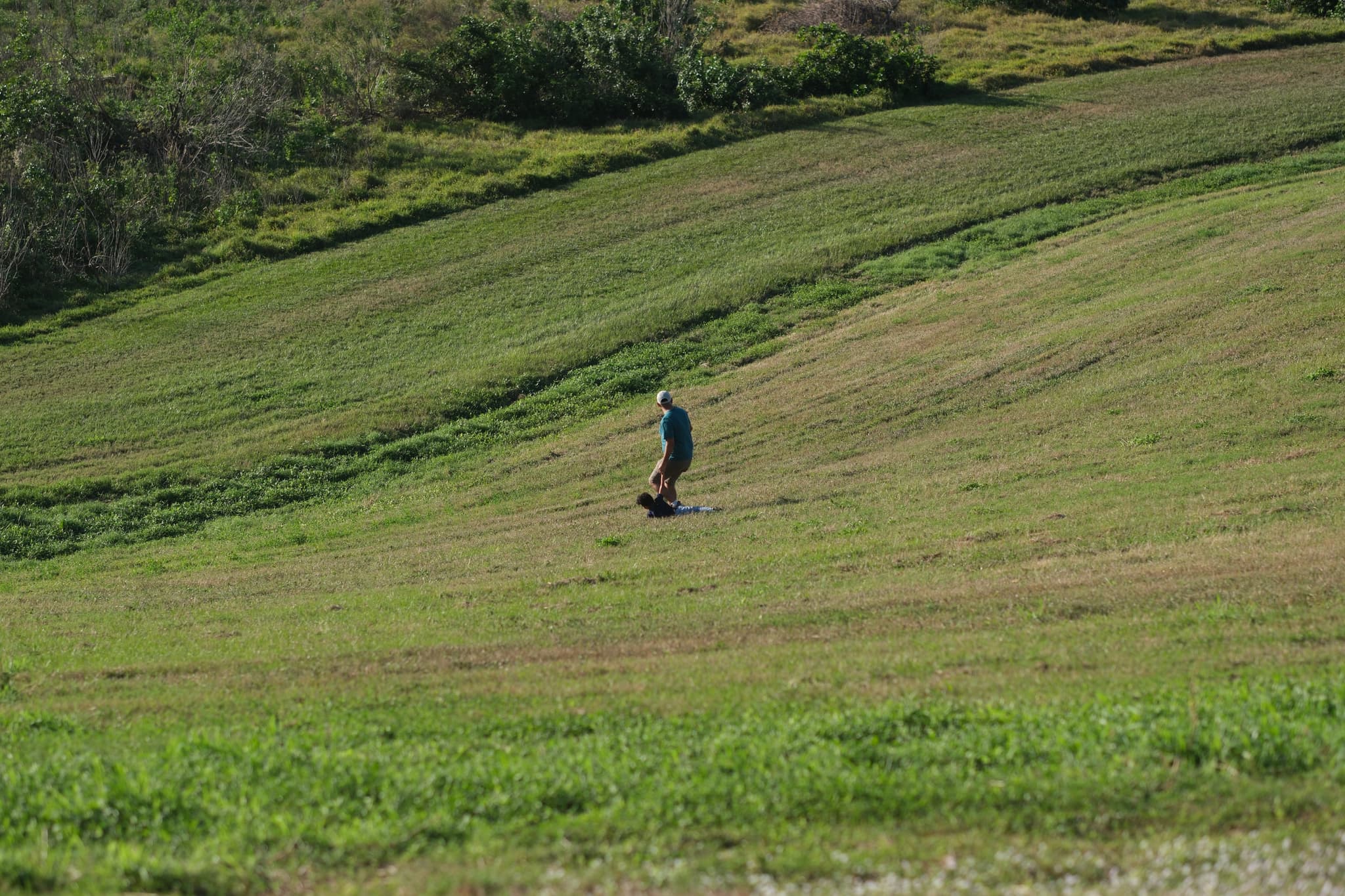 A person riding a mountain board down a grassy hill