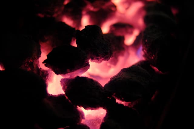 Glowing embers emitting a reddish-orange light in a dark environment