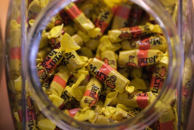 Top-down view into a clear glass jar filled with assorted yellow-wrapped candies