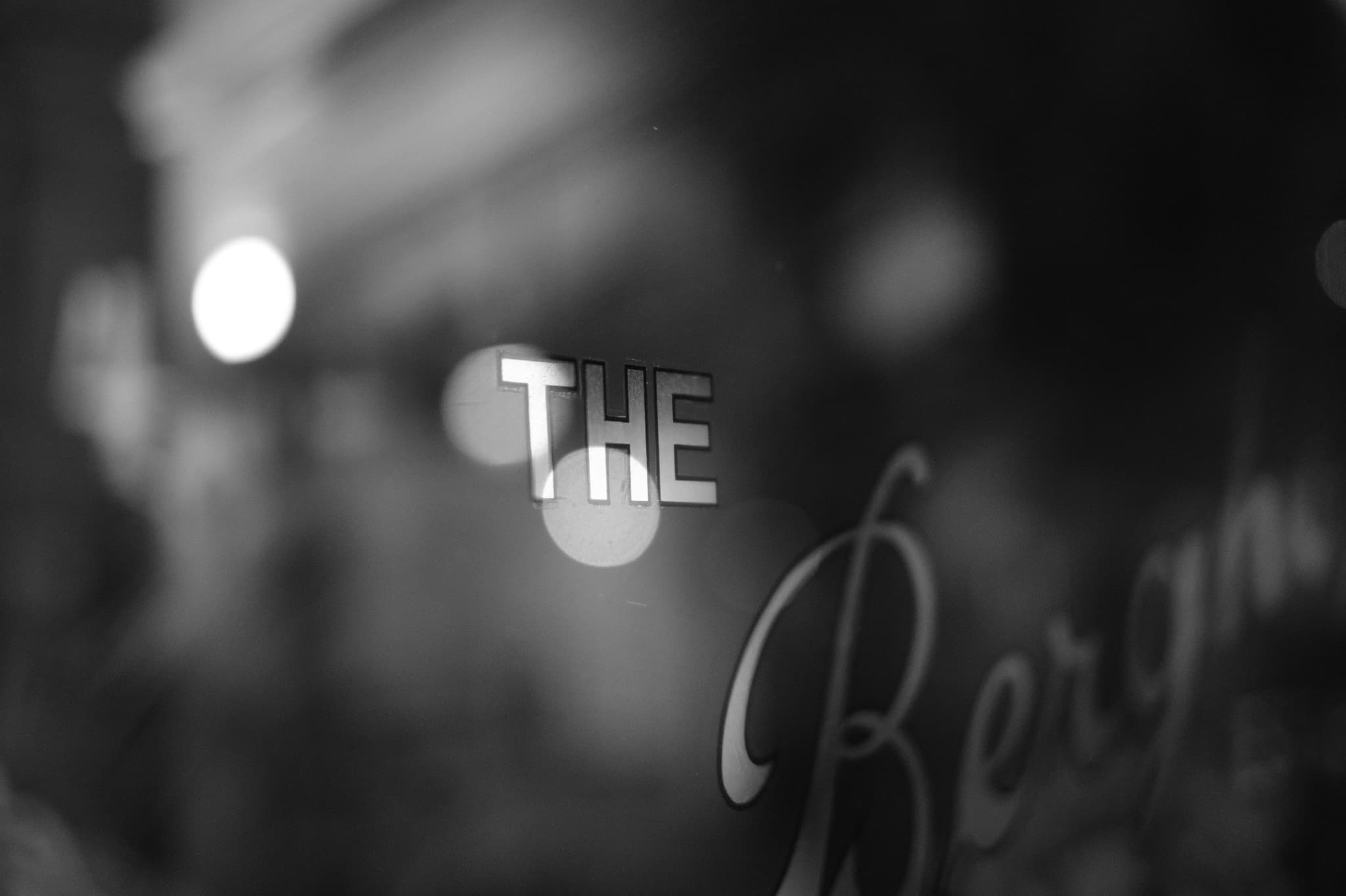 A black and white image with the word THE in focus and Bergman partially visible, set against a blurred background with bokeh lights