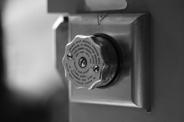 Black-and-white closeup of a machine control knob mounted on a metal panel