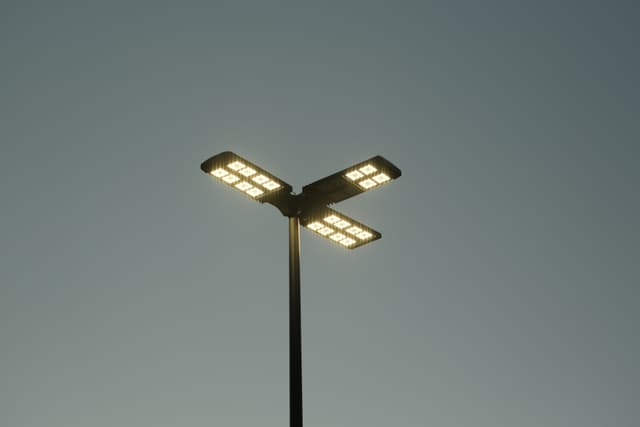 A streetlight with three illuminated arms against a clear sky