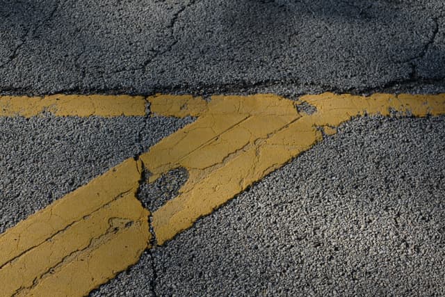 Weathered yellow road markings on cracked asphalt