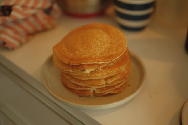 A stack of pancakes on a plate, placed on a kitchen counter