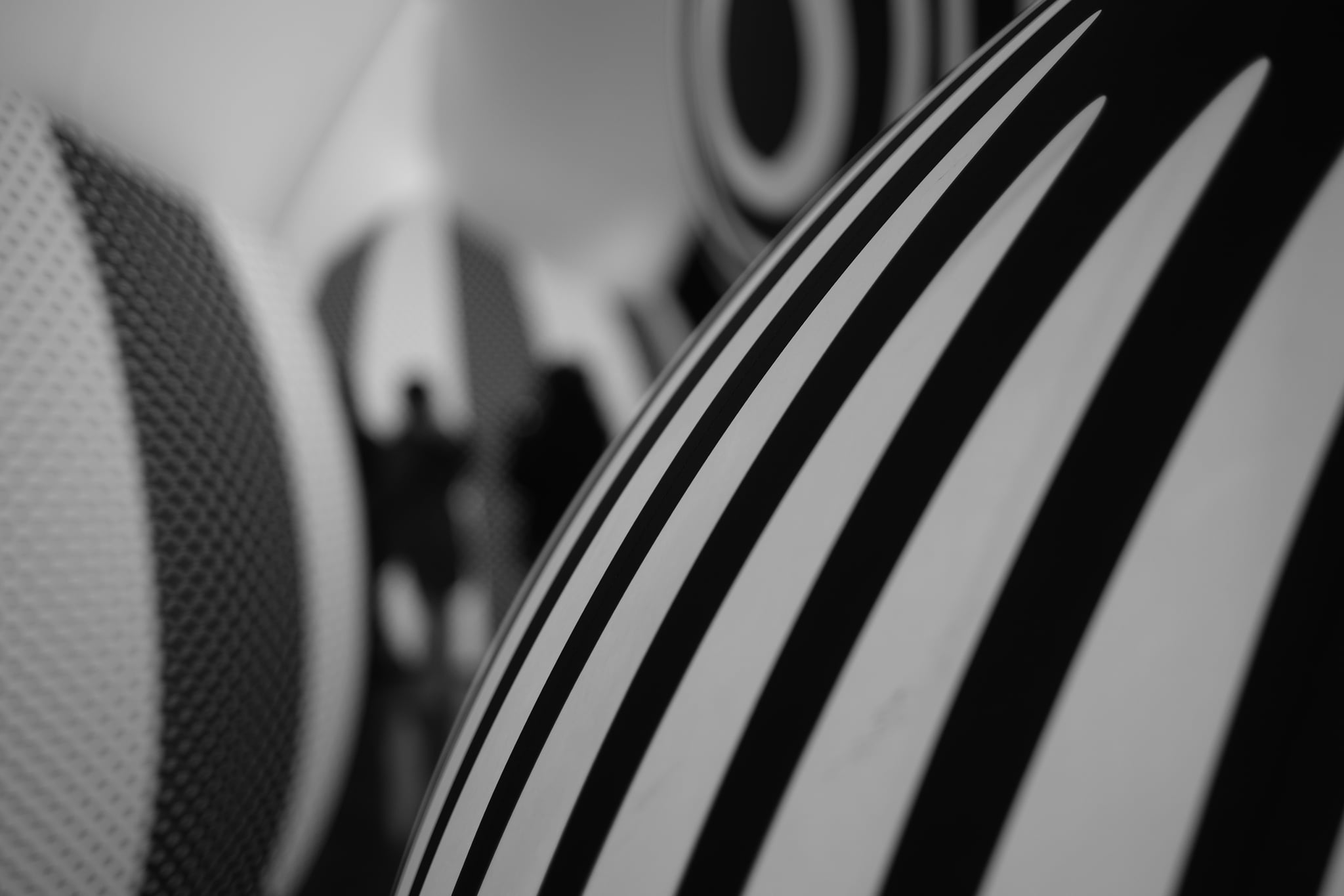 Close-up black-and-white view of curved striped upholstery or padded material with a blurred patterned background