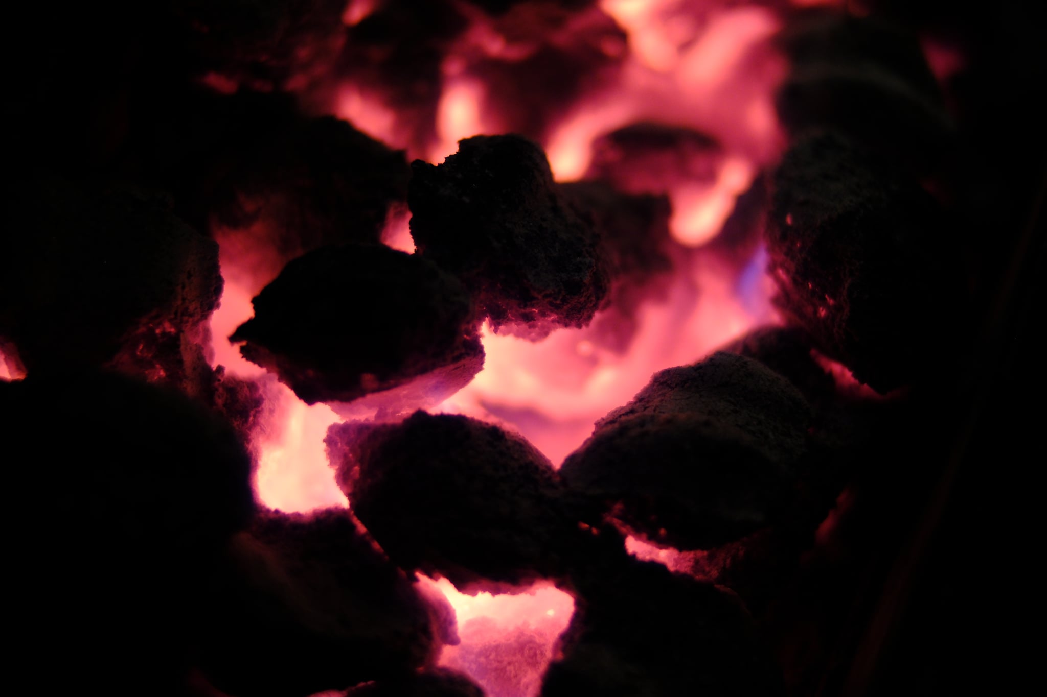 Glowing embers emitting a reddish-orange light in a dark environment