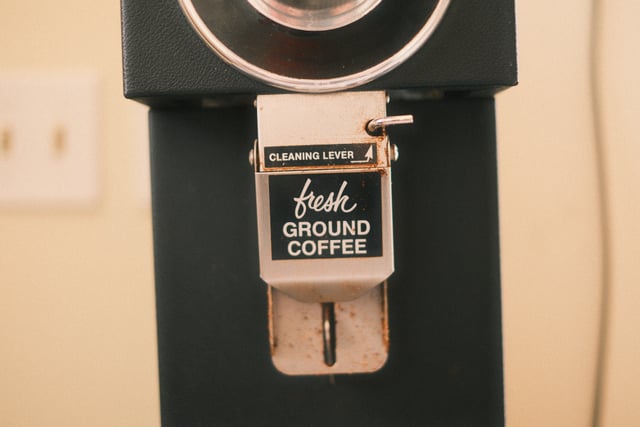 A coffee grinder with a label reading fresh GROUND COFFEE and a cleaning lever
