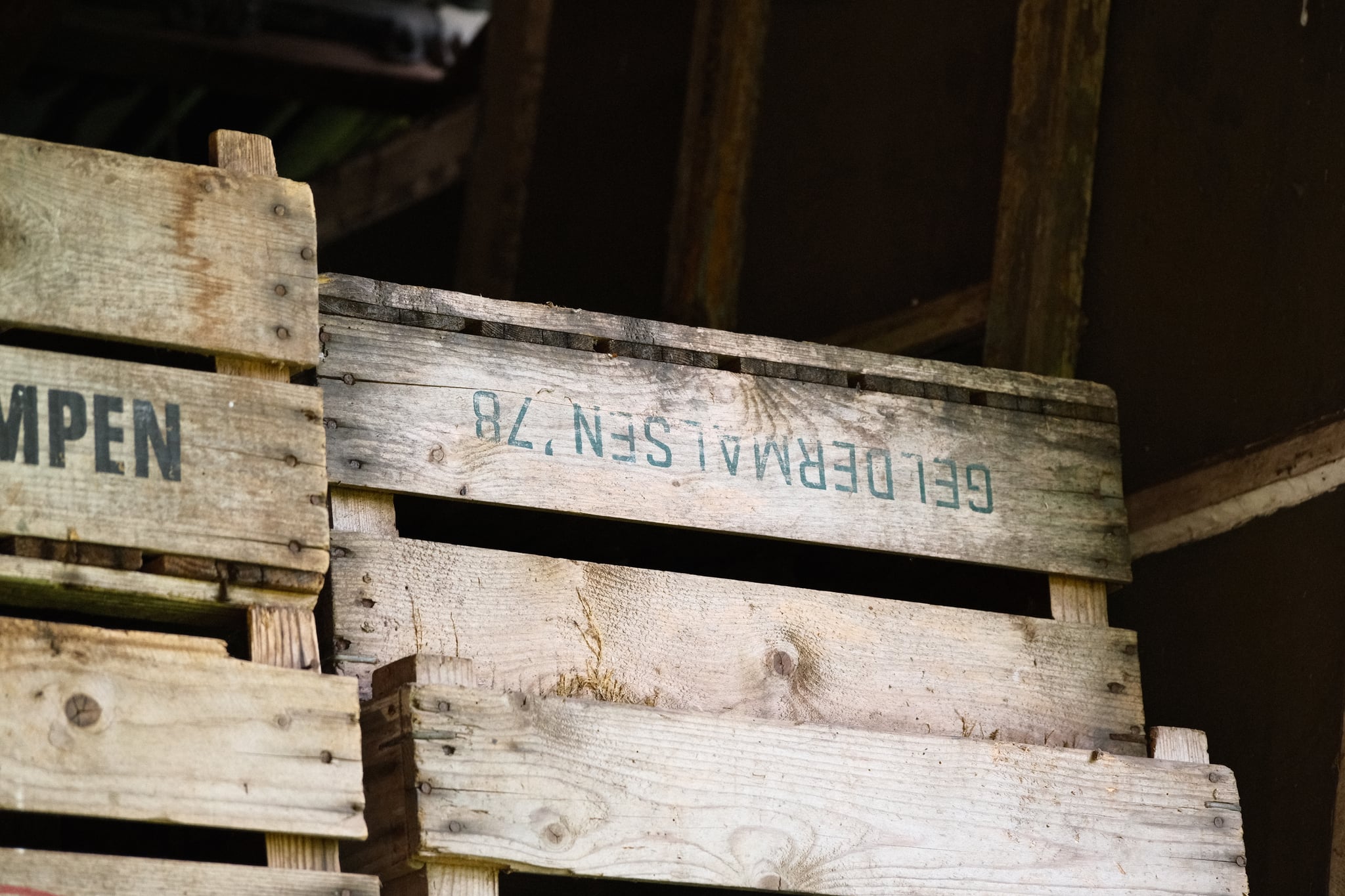 Weathered wooden crates stacked indoors, with faded stenciled lettering on the slats