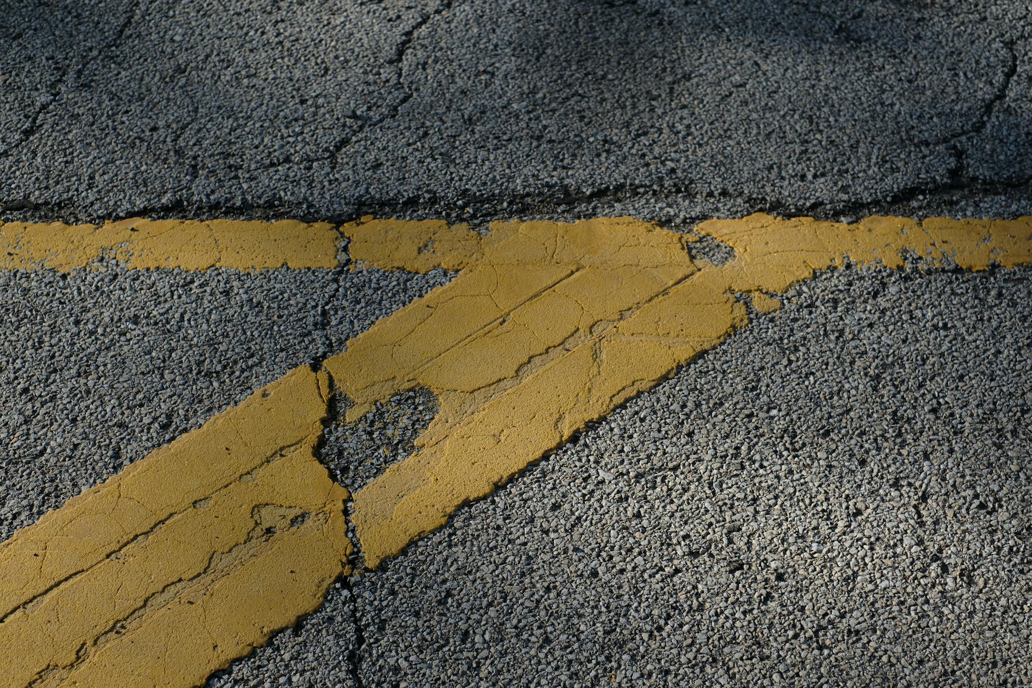 Weathered yellow road markings on cracked asphalt