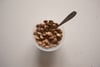 A bowl of cereal with a spoon on a white surface