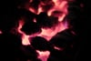 Glowing embers emitting a reddish-orange light in a dark environment