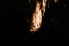 Warm sunlight illuminates rugged rock walls within a dark, narrow cavern