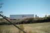 A large white truck trailer with the word Giant and Logistics written on its side, parked in a grassy area with some bushes and trees in the background