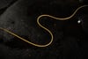 A thin yellow cord winds in graceful curves across a dark, grainy surface