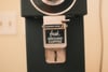 A coffee grinder with a label reading fresh GROUND COFFEE and a cleaning lever